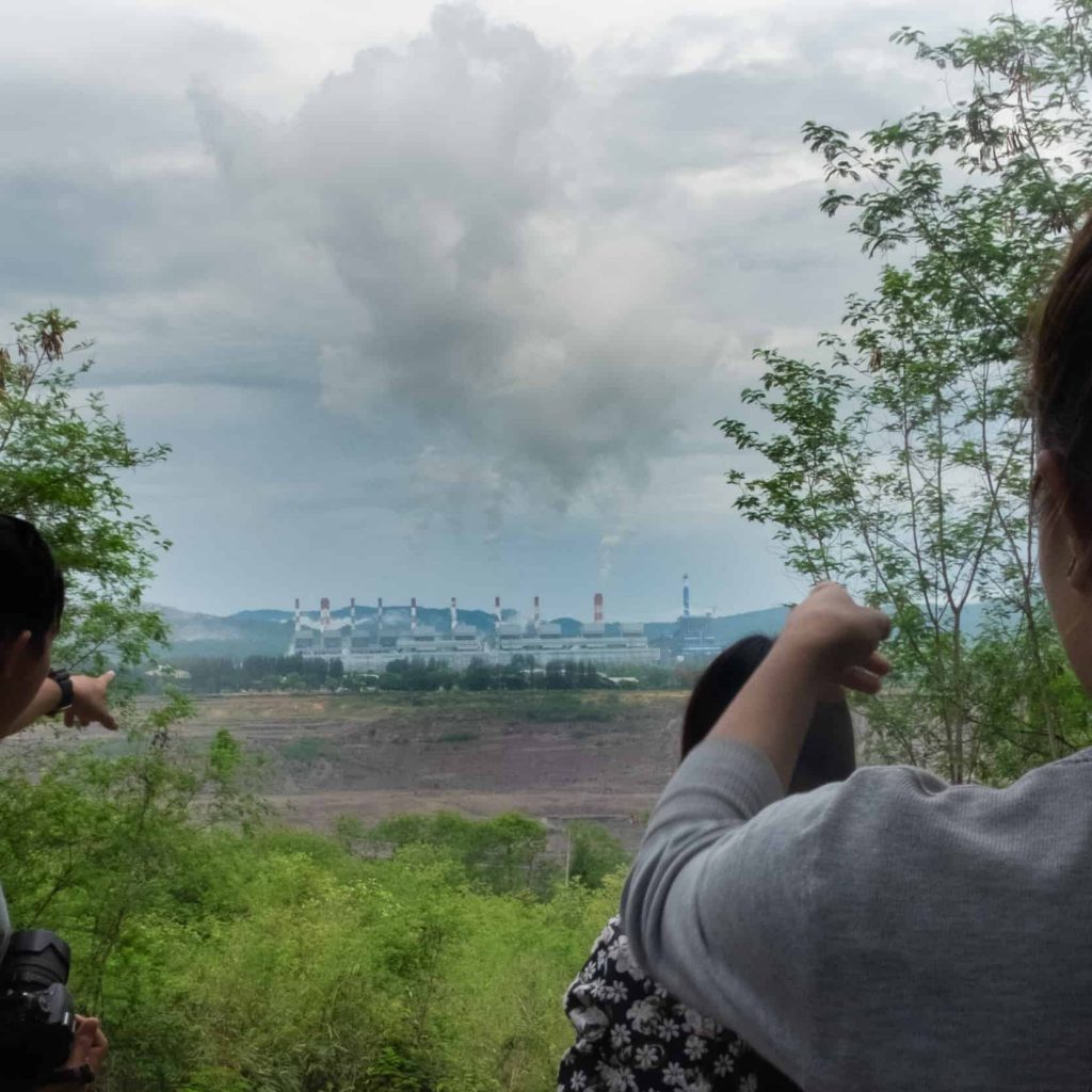 Community members from Nan look out at the Mae Moh open-pit lignite coal mine and power plant.
