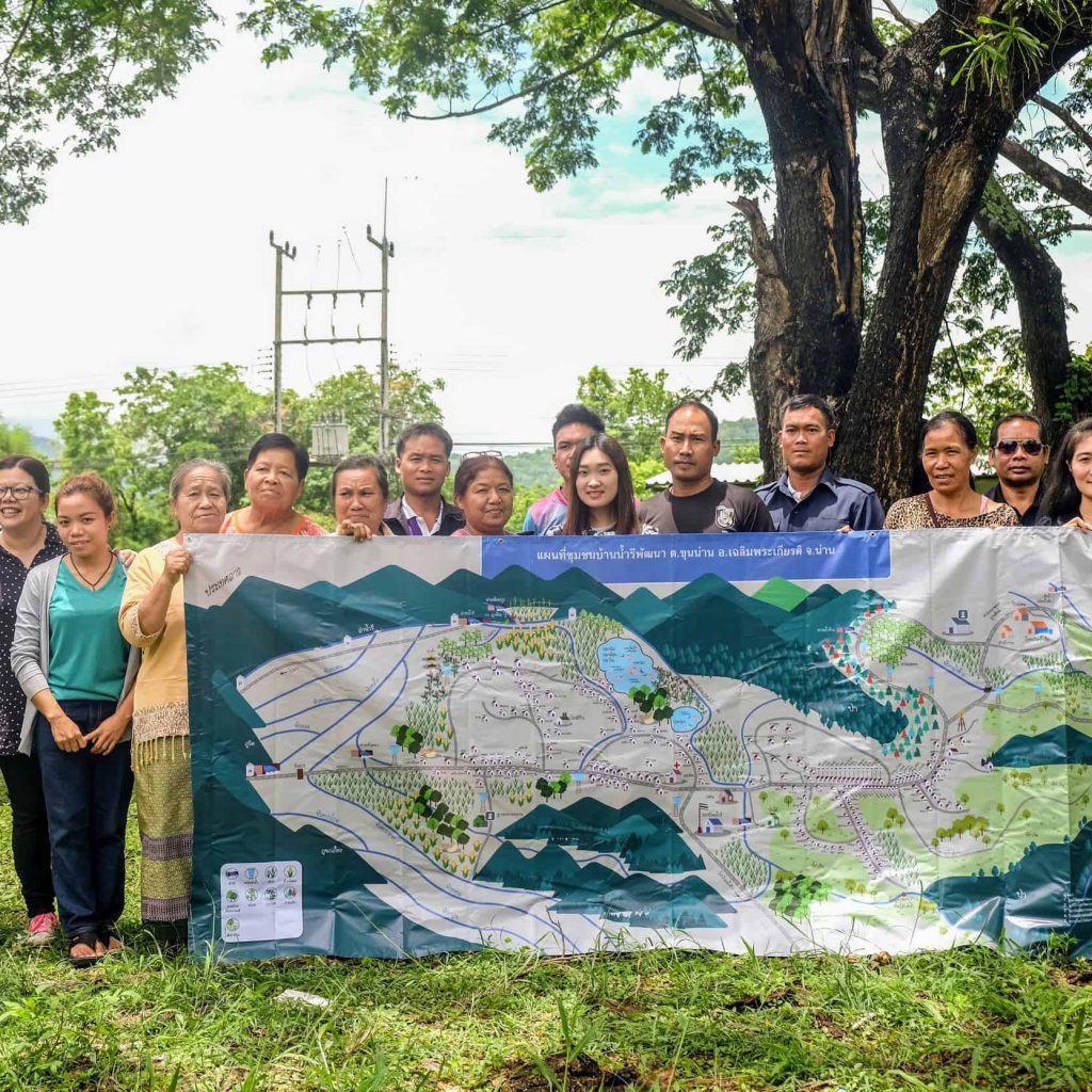 Members of the Mae Moh and Nan communities pose with a map of one of the Nan communities, showing crops, rivers and watersheds.